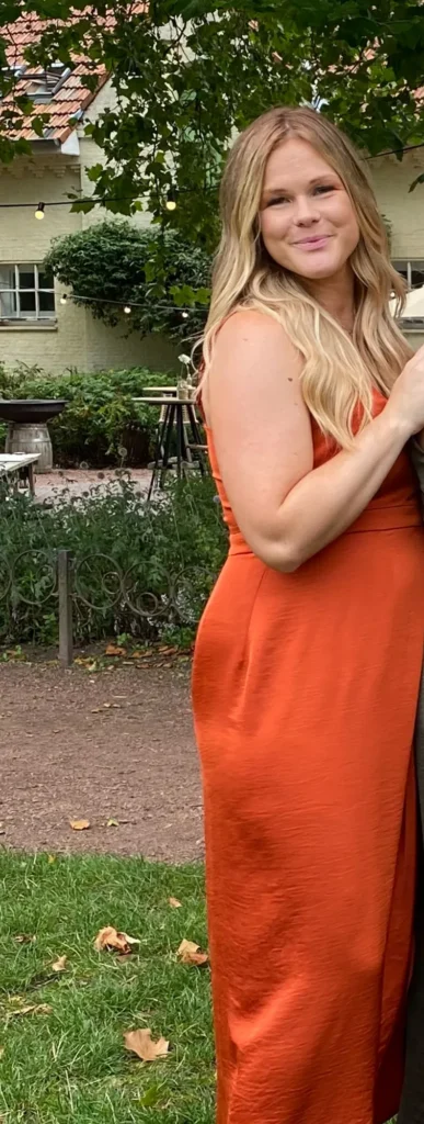 Caro, klant van Focus-On, in een oranje jurk in een tuin