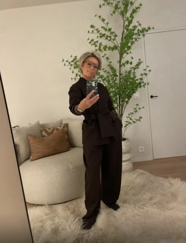 Nancy, klant van Focus-On, in een bruin pak in haar woonkamer