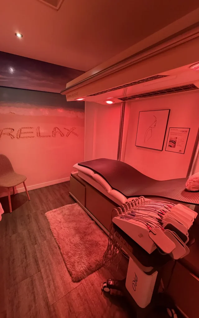 Rustige behandelruimte met warm rood licht en behandelbed